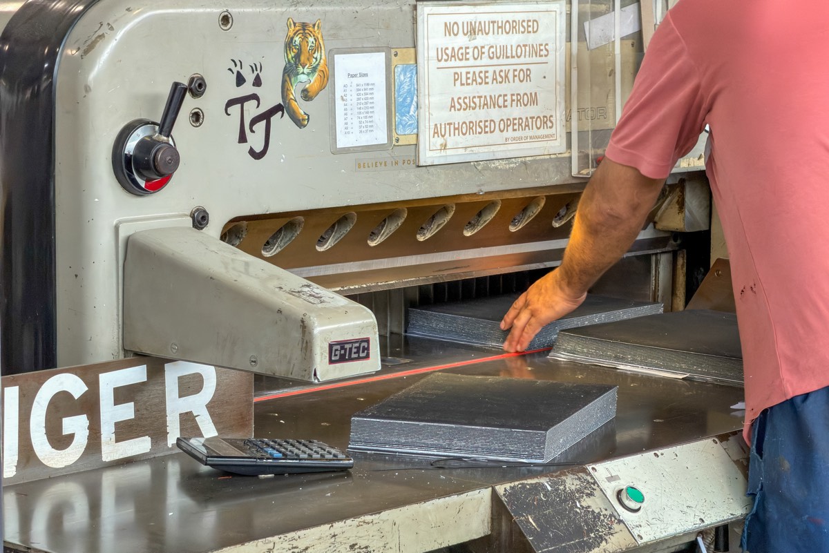 Guillotine operator squaring a stack of board